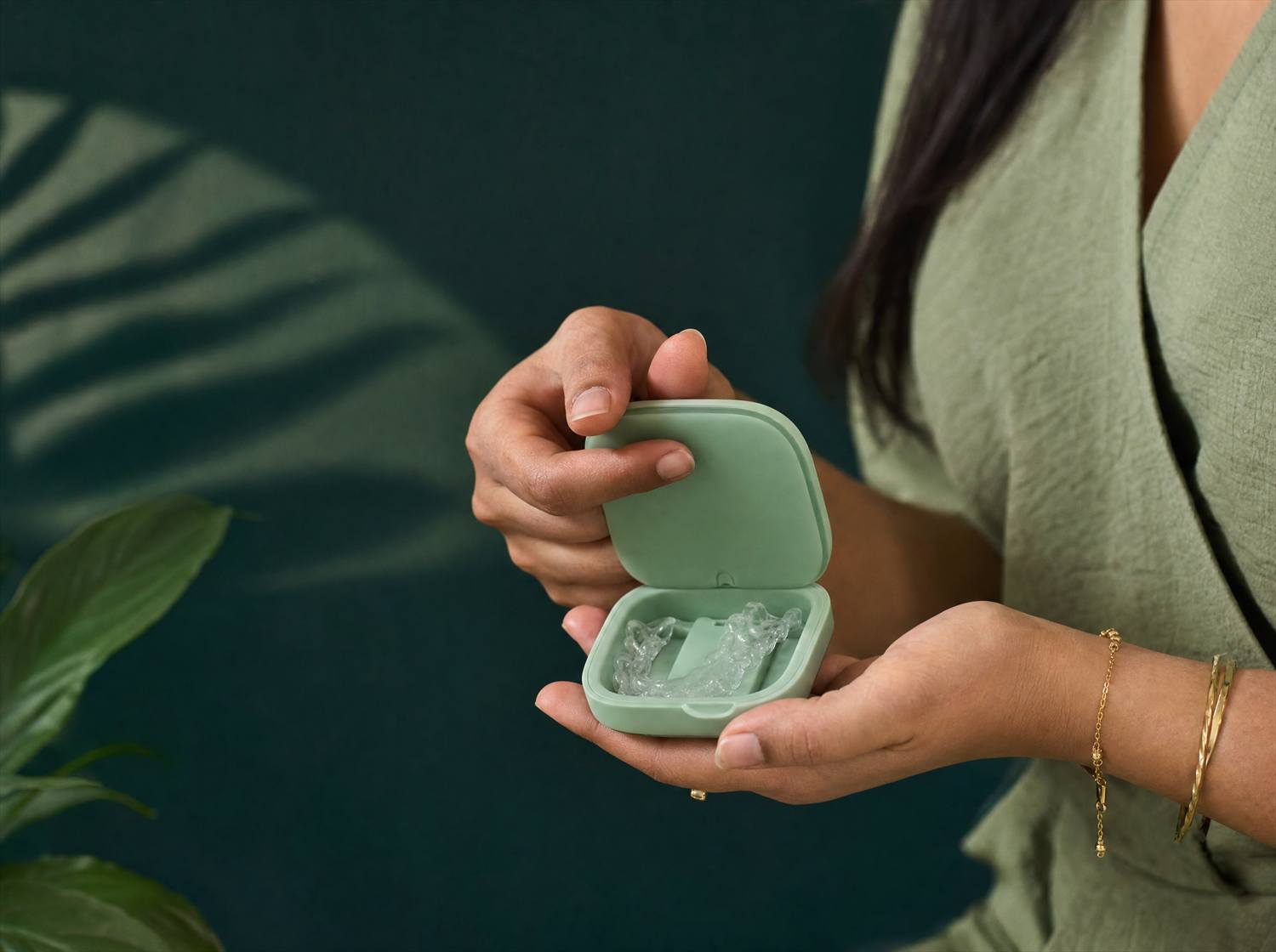 Hands holding the mint-green aligner travel case